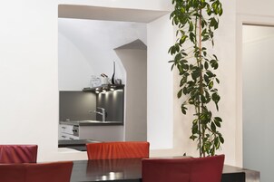 Ein moderner Essbereich mit Tisch und Stühlen, eine Küche im Hintergrund und ein Blumentopf.