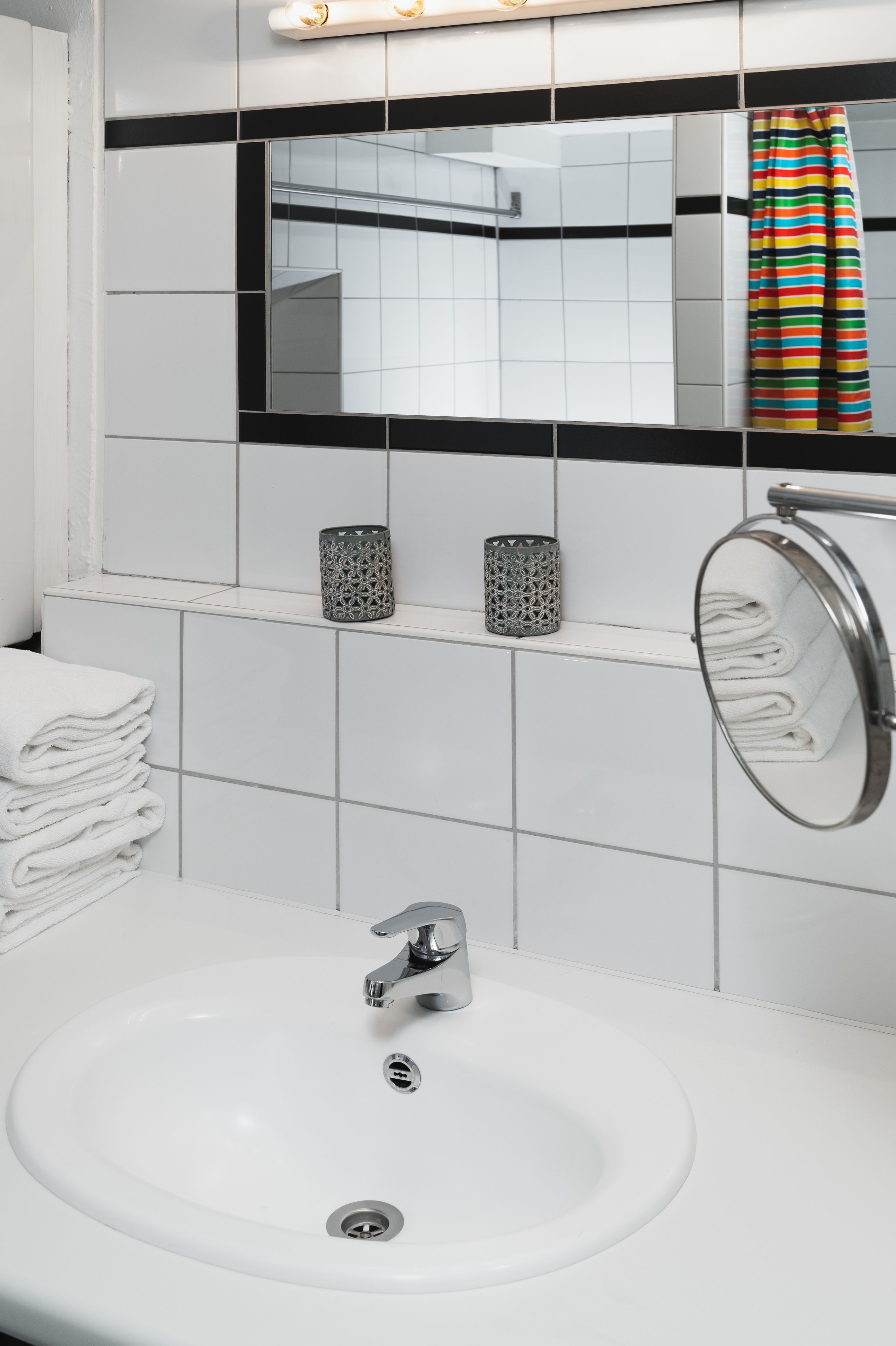 Een badkamer met een witte wastafel, een spiegel en een badgordijn met strepen.