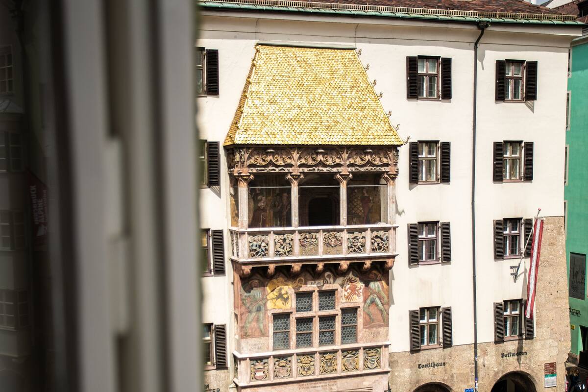 A historic building with a prominent balcony and a green dome.