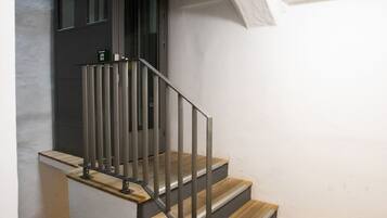 A staircase with wooden steps and metal railings, leading to a dark door.