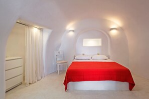 A bedroom with a bed, a chair, a dresser, and a window with curtains.