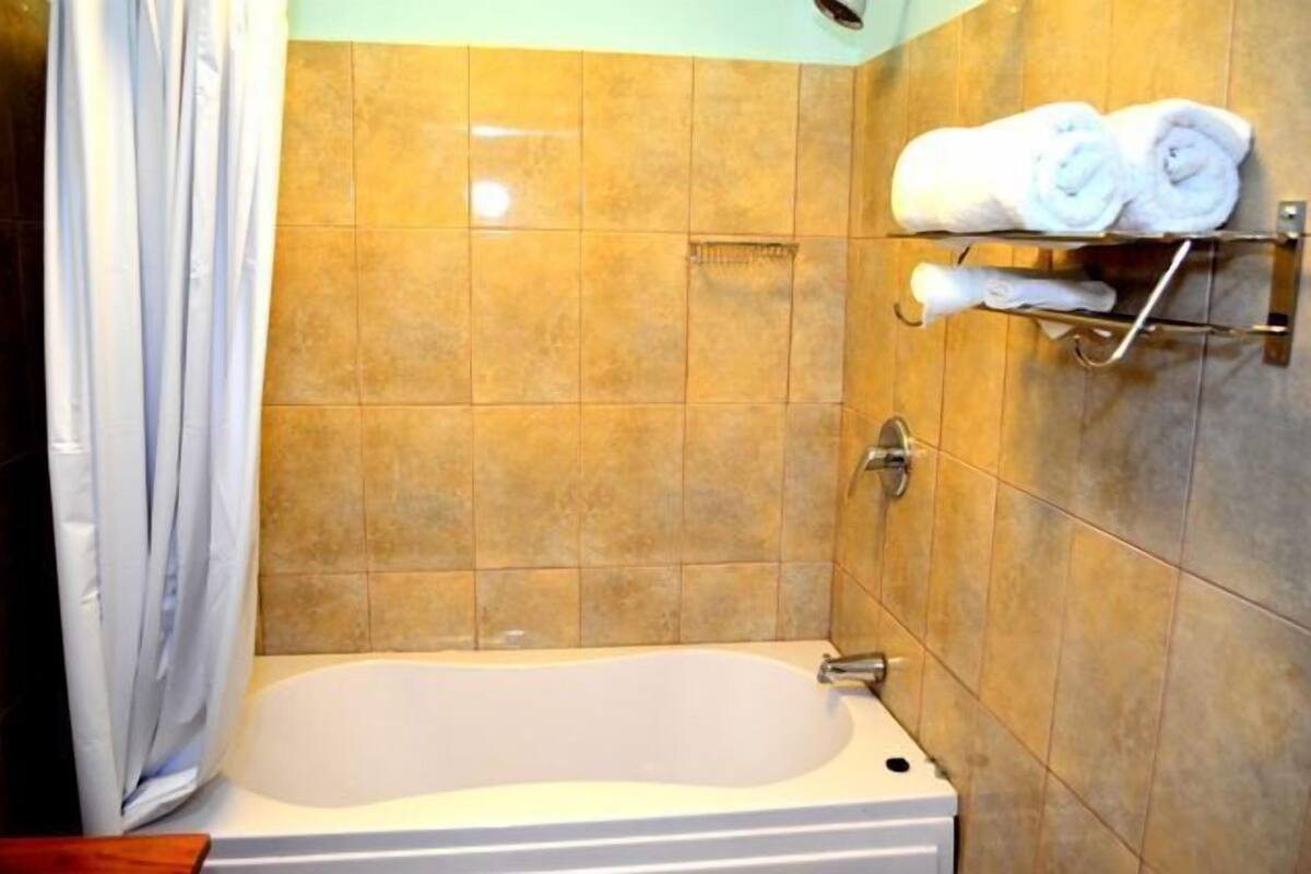 A bathroom with a bathtub, tiled walls, and a towel rack with towels.