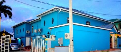 A two-story building with a blue exterior, a white door, and a small balcony.