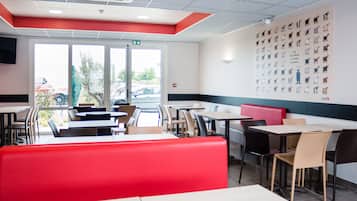 Un interior de restaurante con cabinas, mesas y una pared de ilustraciones de animales.