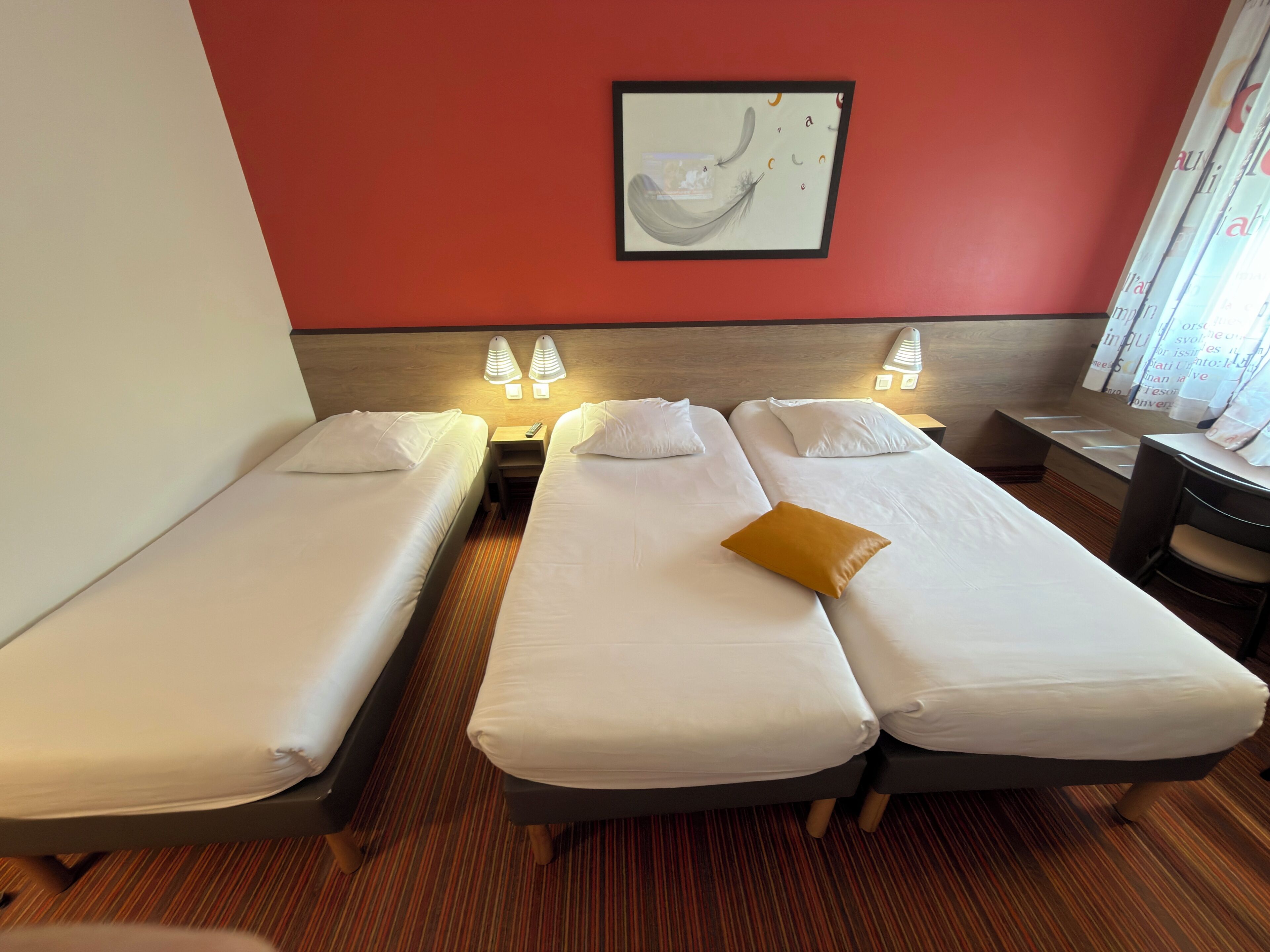 Ein Hotelzimmer mit zwei Einzelbetten, einem kleinen Schreibtisch und einem Stuhl.