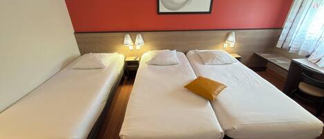 Ein Hotelzimmer mit zwei Einzelbetten, einem kleinen Schreibtisch und einem Stuhl.