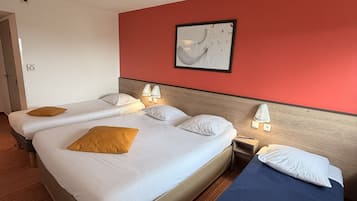 Una habitación de hotel con dos camas, una pared de acento roja, una obra de arte enmarcada y una lámpara en el techo.