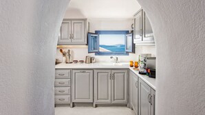 Una cocina estrecha con gabinetes grises, un ventanal con vista al mar y una cafetera.