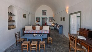 Una habitación acogedora con sofá, una mesa de madera y sillas, un escritorio con silla y una estantería.
