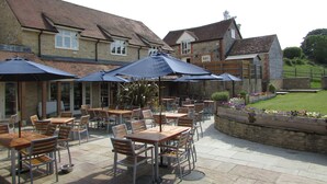 An outdoor patio with tables and chairs, surrounded by stone walls and a garden. - The Kings Arms (Sherborne)