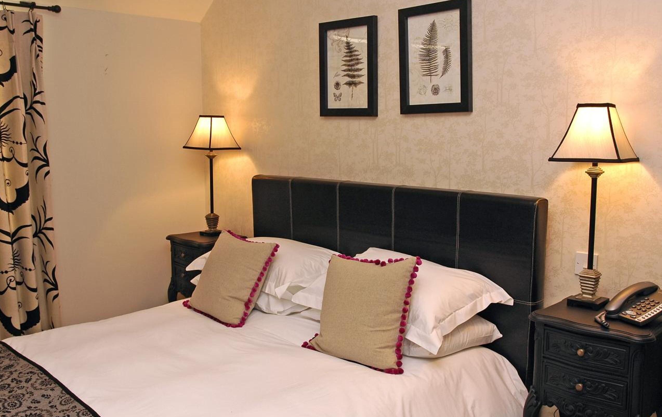 A neatly made bed with two pillows, a headboard, and two bedside tables with lamps.