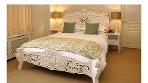 A classic bed with ornate carvings, a matching headboard, and green pillows. - The Kings Arms (Sherborne)