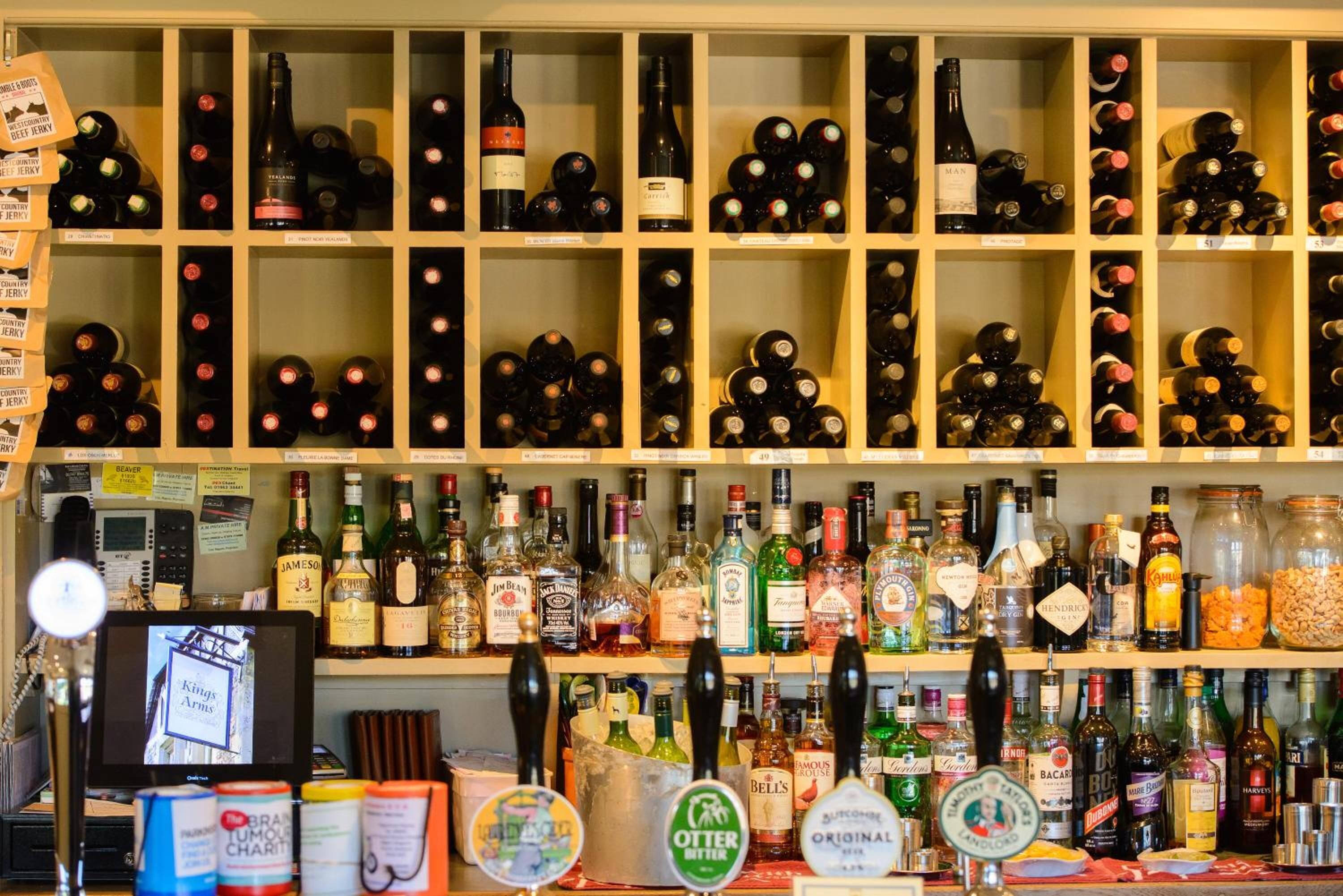 A bar with shelves of various liquor bottles and a computer monitor.