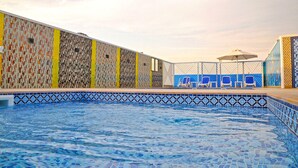A swimming pool with a tiled edge, a fence, and a few chairs. - Alain Hotel Ajman (Ajman)