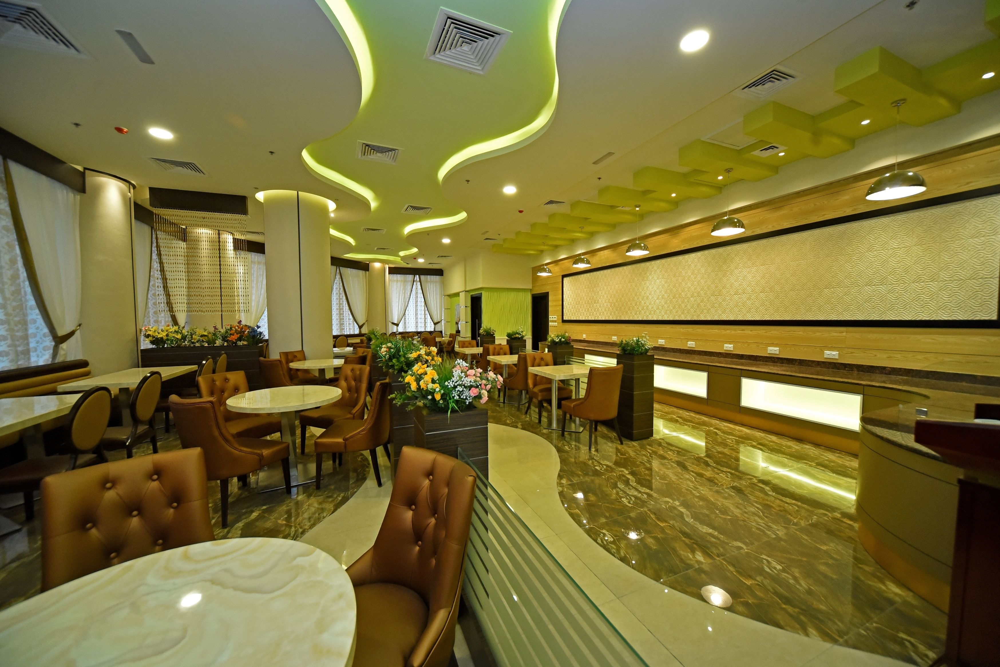 Una hall d'hotel moderna con pavimento in marmo, sedute in pelle e un'area reception con un bancone in legno.
