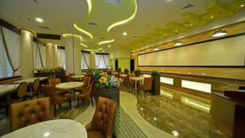 Una hall d'hotel moderna con pavimento in marmo, sedute in pelle e un'area reception con un bancone in legno.
