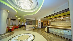 A hotel lobby with a large circular carpet, a reception desk, and a chandelier. - Alain Hotel Ajman (Ajman)