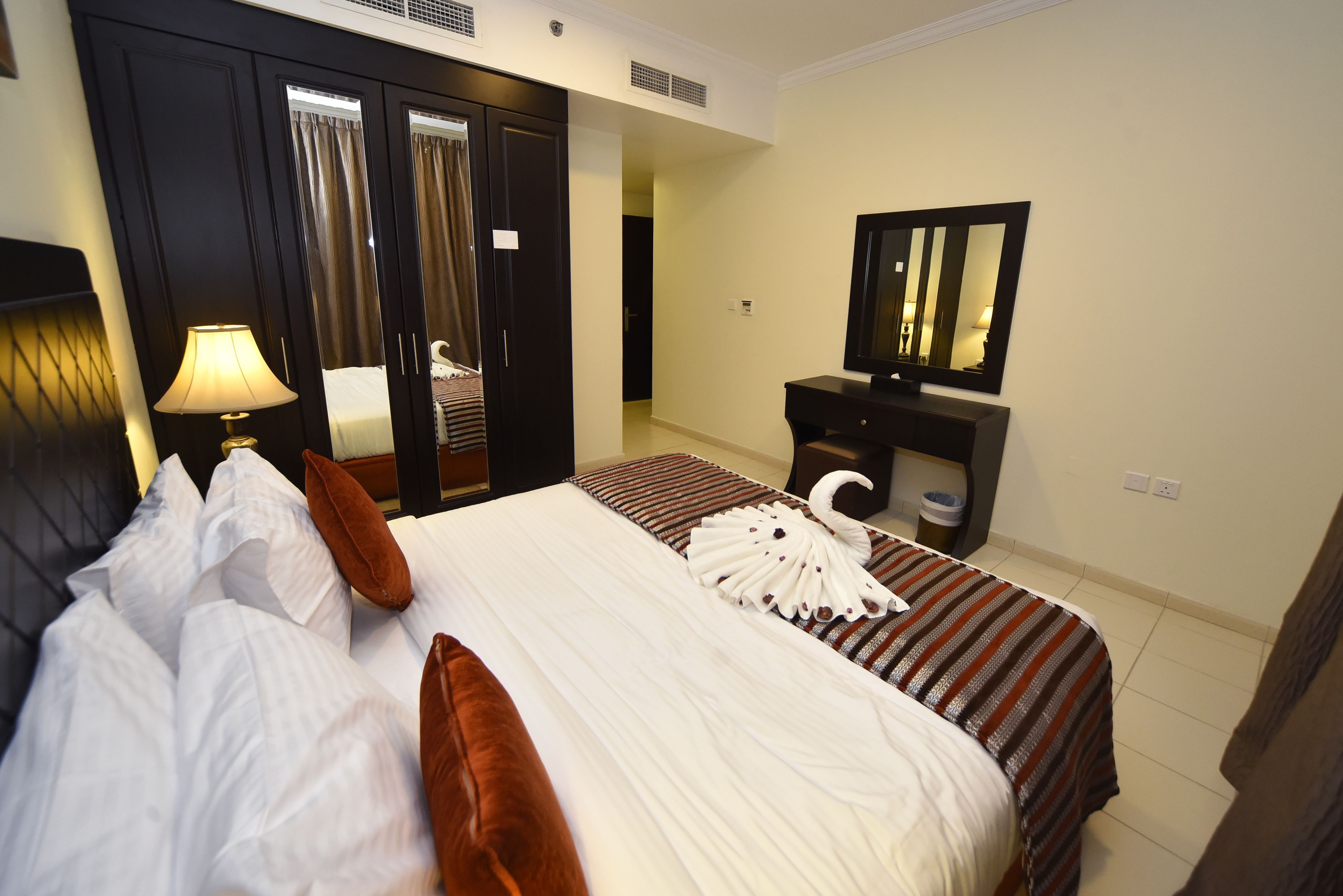 A hotel room with a bed, a nightstand, a mirror, and a wardrobe.
