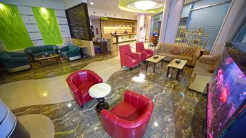 Una hall con una reception, sedute rosse e beige, un tavolino da caffè e un grande acquario.
