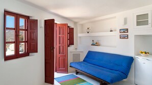 A compact living space with a blue sofa, a white table, and a colorful rug. - Villa Amalia (Santorini)