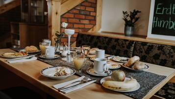 A breakfast table set with plates, cups, and a variety of food items.