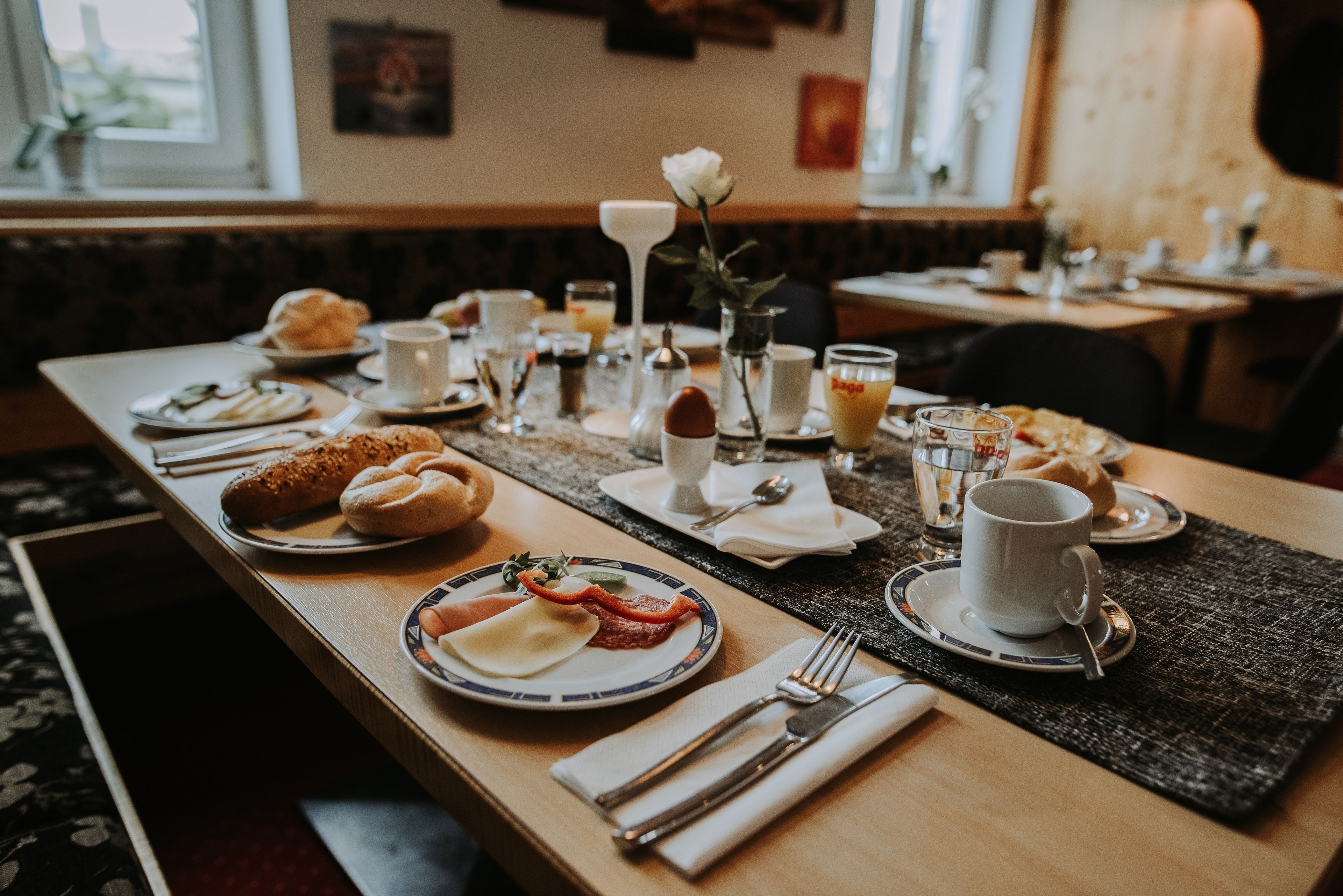 Una mesa de desayuno con diversos platos, entre ellos, croissants, huevos y un vaso de jugo.