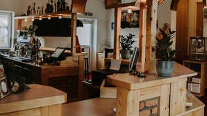 Een bar met houten meubels en bakstenen details, met een toonbank, zitplaatsen en een plafondventilator.