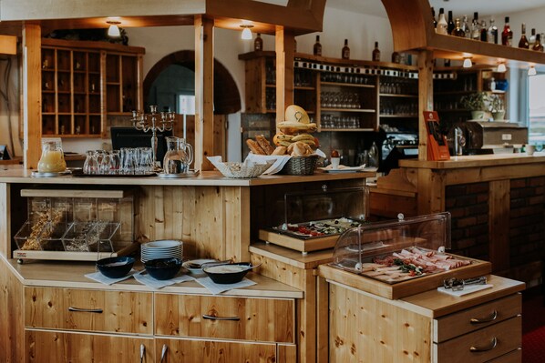 Un buffet pour le petit-déjeuner proposant du pain, des viennoiseries et un espace dédié au café.
