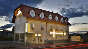 Een hotel met twee verdiepingen, een dak met rode tegels, meerdere ramen en een bord waarop een pizzeria wordt aangeboden.