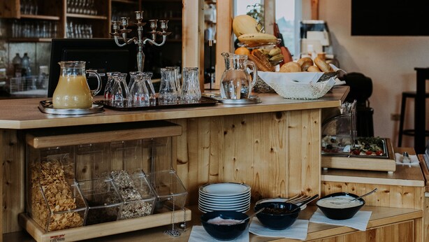 Een bar met houten planken, flessen, glazen en diverse etenswaren.