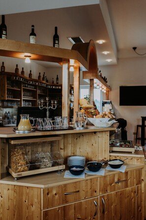 A bar area with wooden shelves, bottles, glasses, and a variety of food items. - Gästehaus Feldkirchen (Feldkirchen bei Graz)