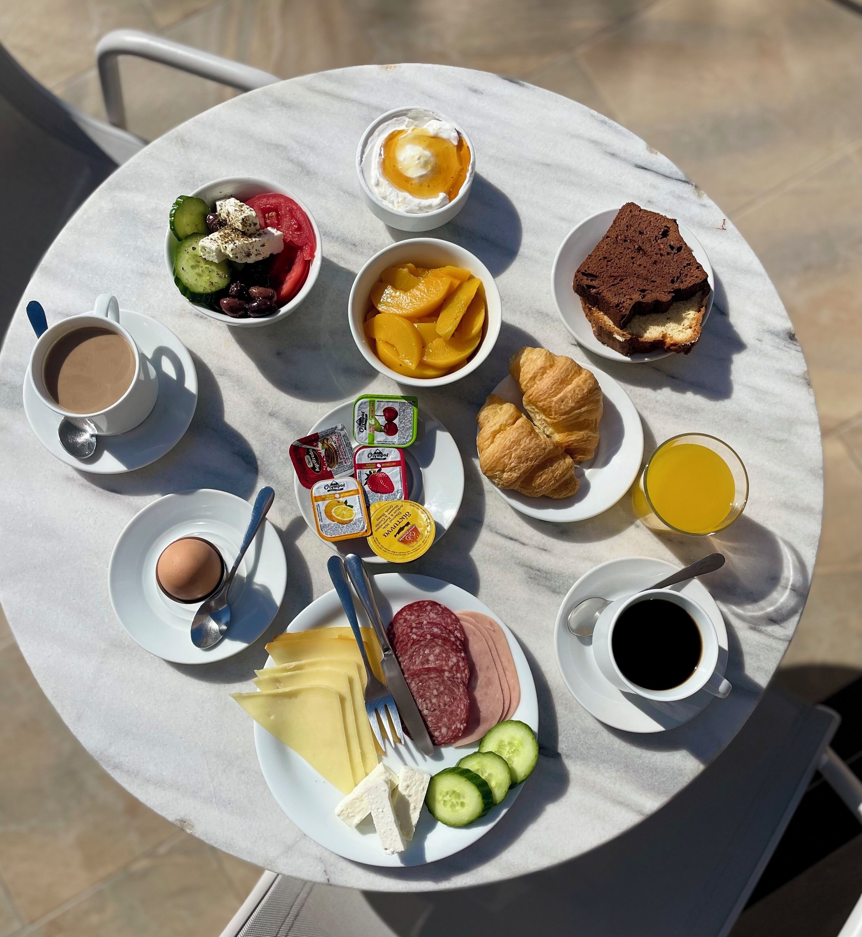 A round table with a variety of breakfast items including eggs, cheese, ham, and pastries.