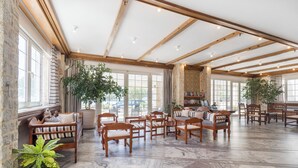 Una habitación amplia con muebles de madera, ventanas grandes y una pared de piedra.