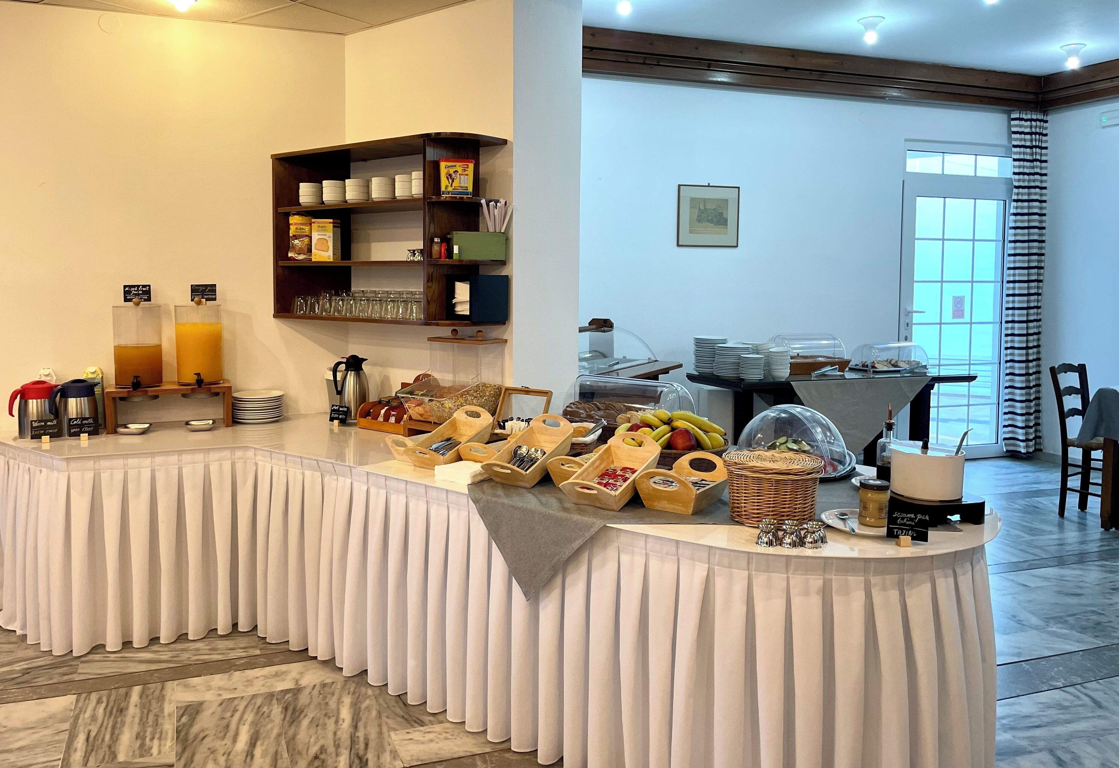 A breakfast buffet setup with various food items, drinks, and utensils.