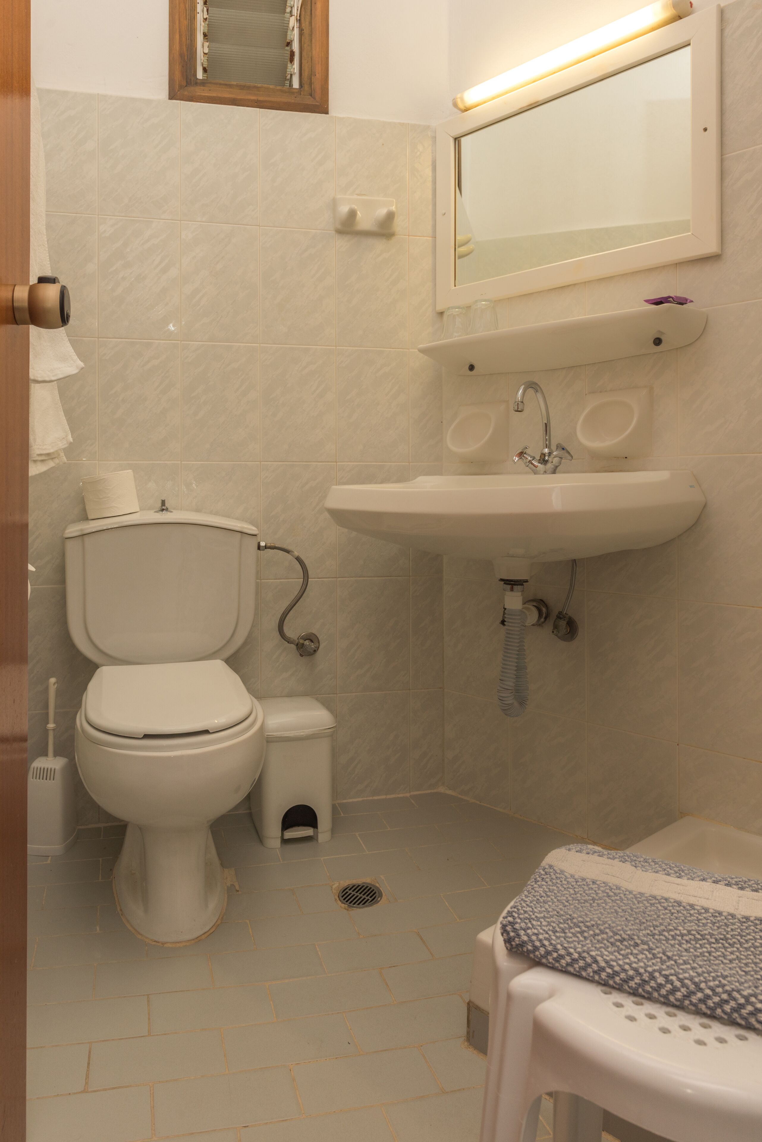 A small bathroom with a toilet, sink, and mirror.