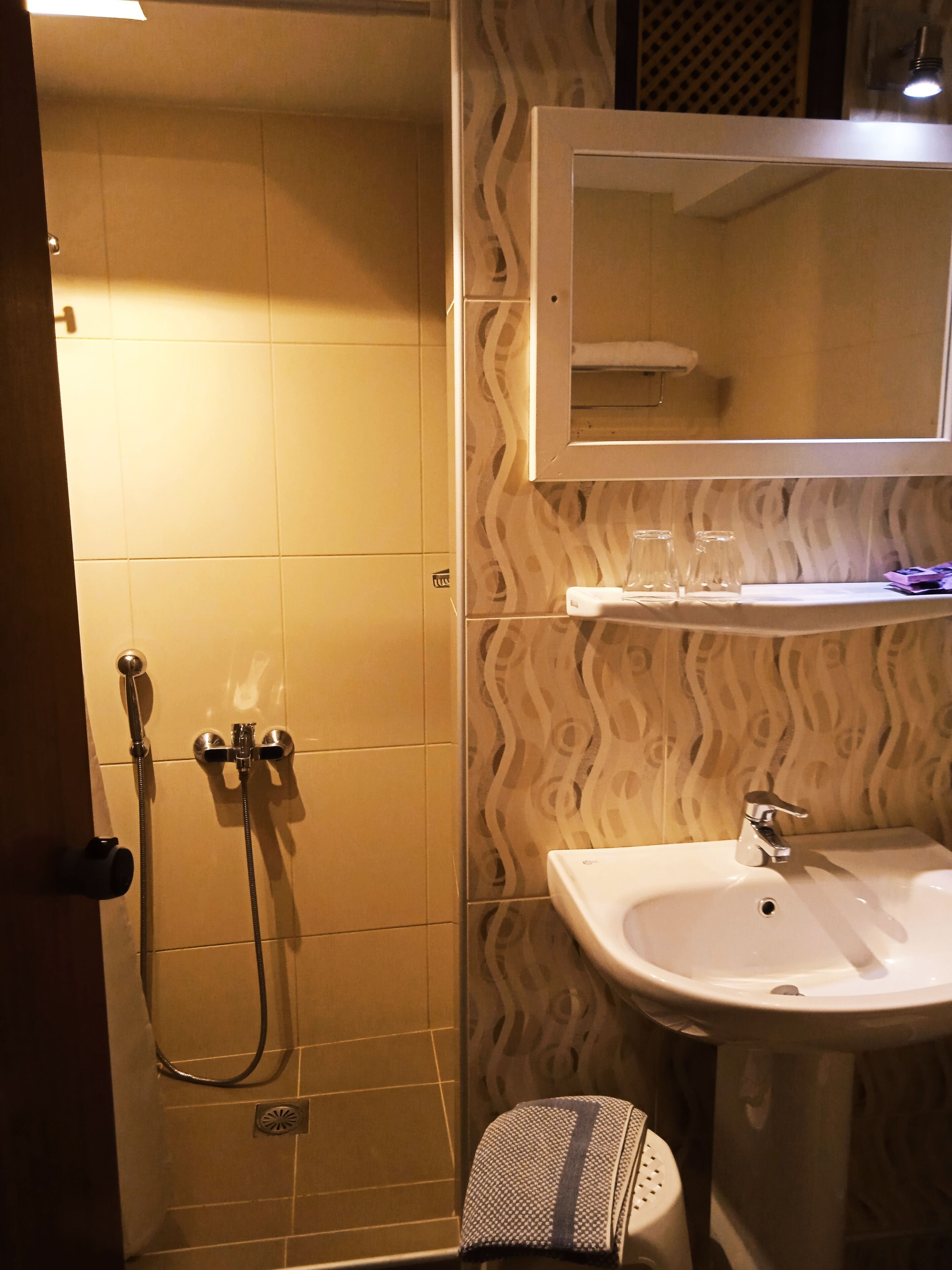 Une salle de bain avec une douche, un lavabo et un miroir au-dessus du lavabo.