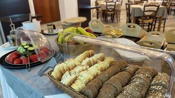 A buffet table with various food items including bread, fruits, and vegetables.