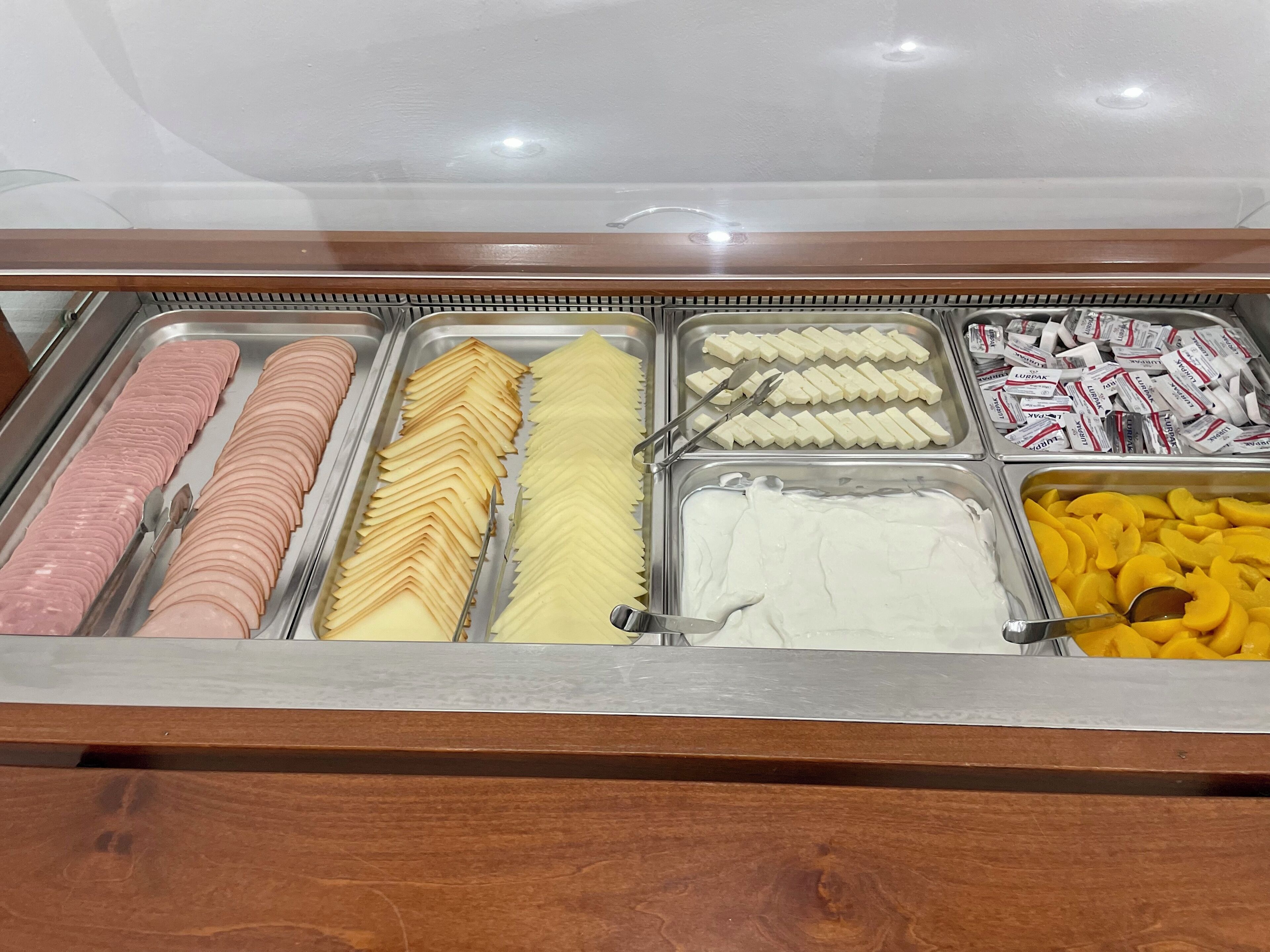 Un buffet proposant une variété de plats, notamment des viandes et des fromages en tranches, ainsi que des fruits.