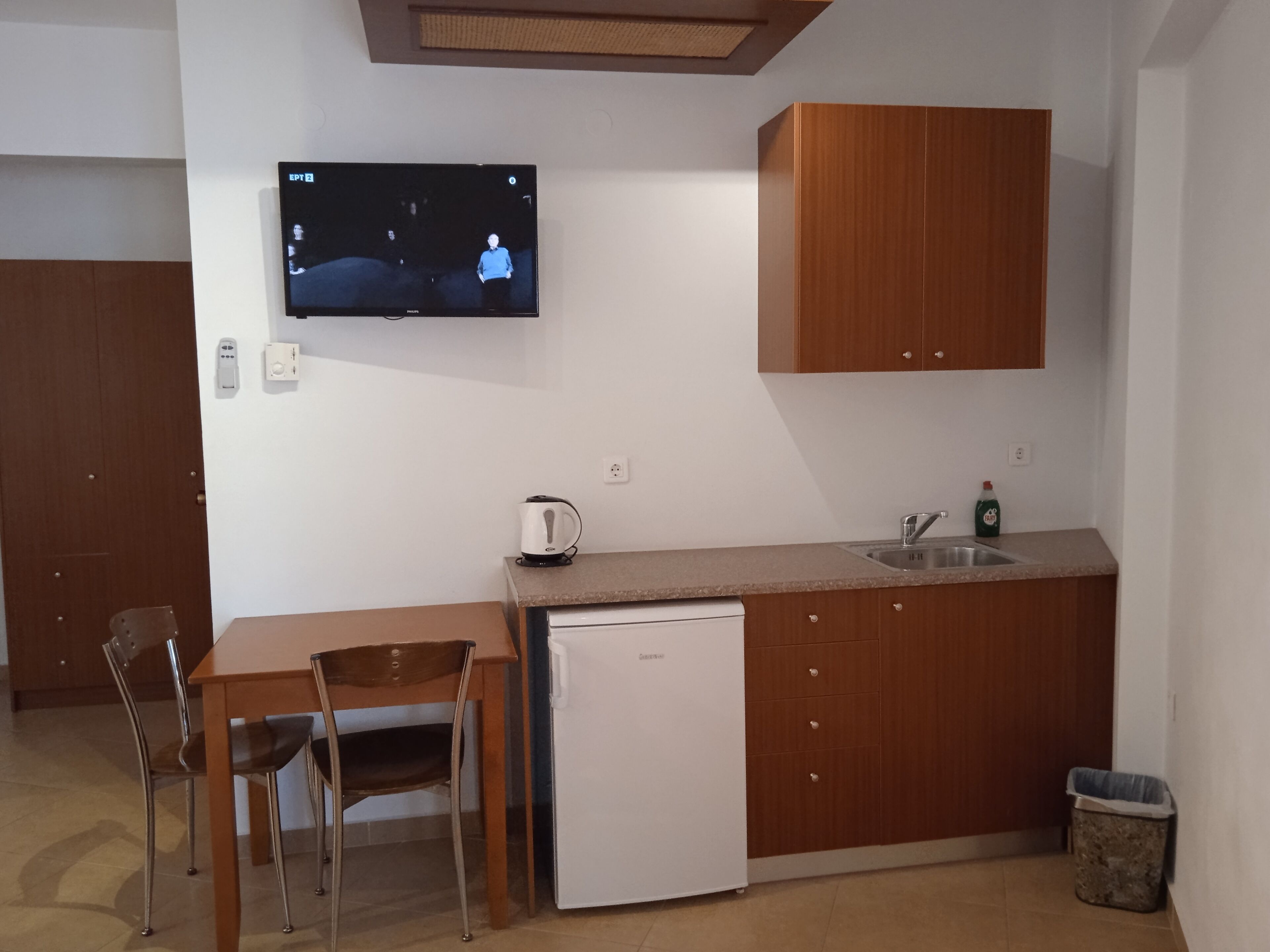 Eine kleine Küche mit einem Einbaukühlschrank, einem Wasserkocher und einem Spülbecken.