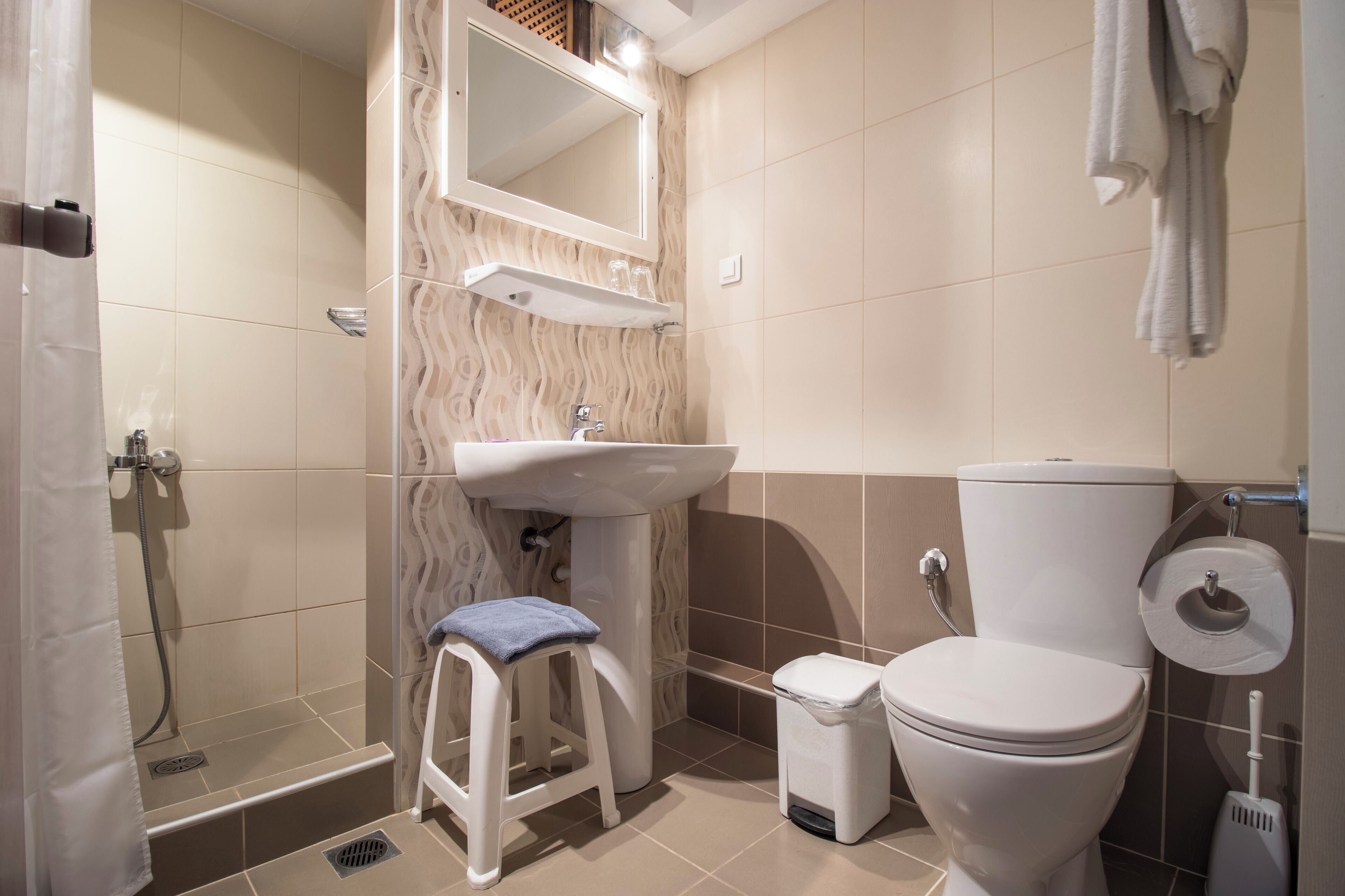 A bathroom with a shower, sink, toilet, and a towel rack.