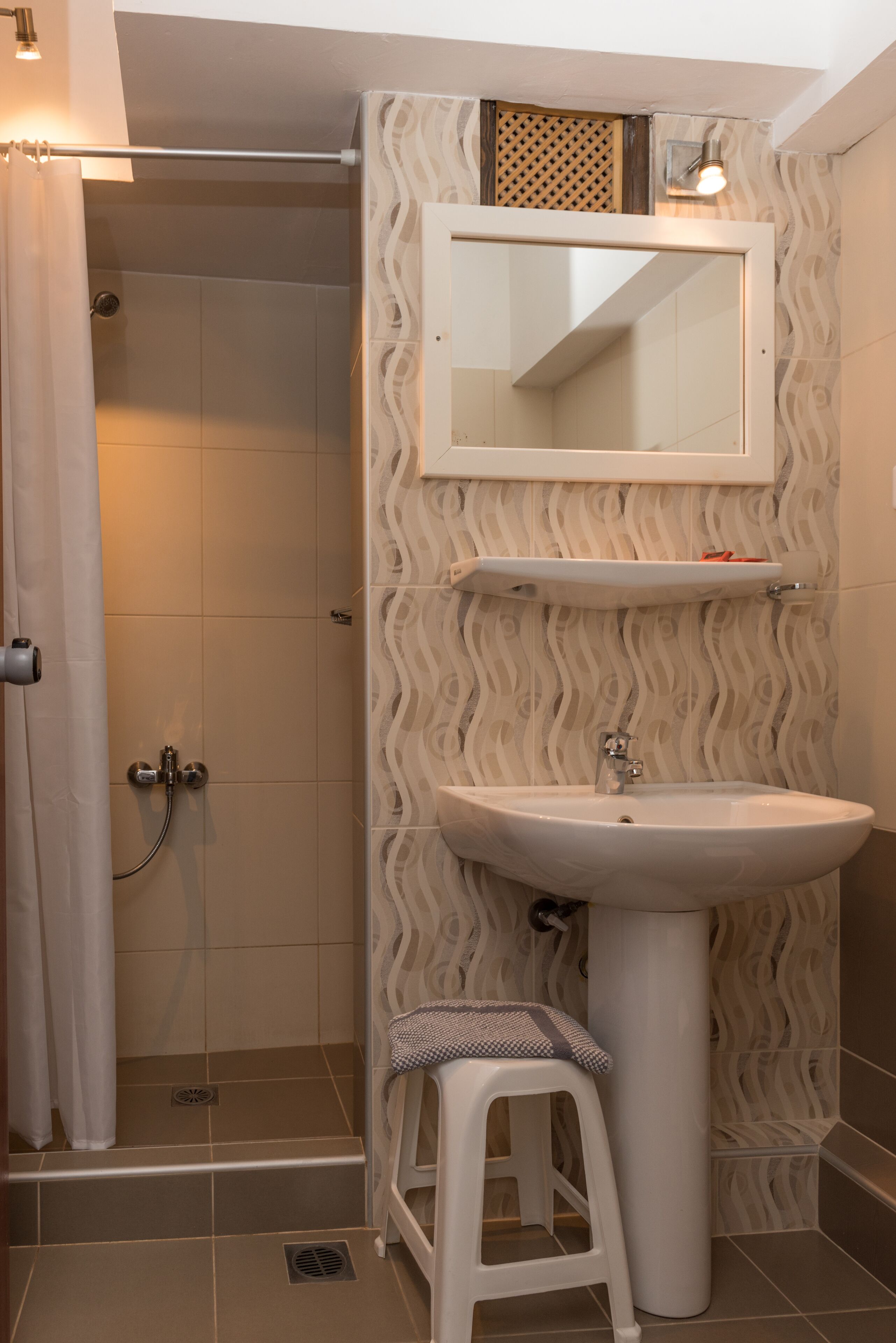 Ein Badezimmer mit Dusche, Waschbecken, Spiegel und einer Wand mit Muster.