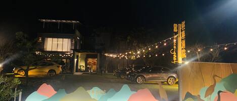 A building with a brightly lit entrance, a car parked in front, and decorative lights.