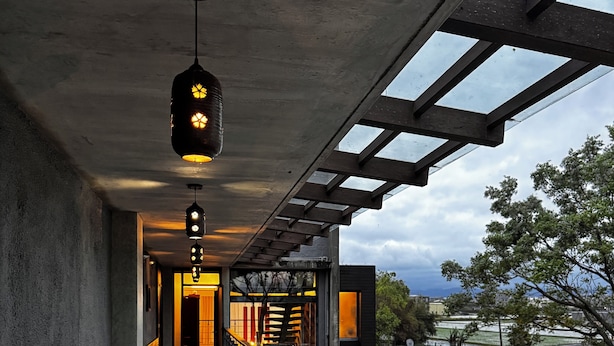 A covered outdoor corridor with a stone floor, metal railings, and hanging pendant lights. - Serene Gray (Wujie)