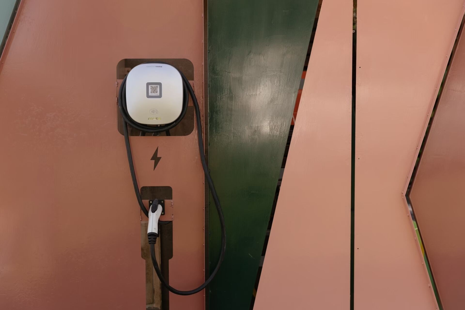 Estación de carga con un código QR y un símbolo de rayo en una pared.