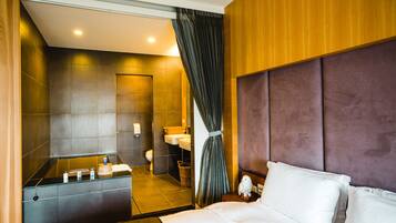 A modern hotel room with a large bed, a bathroom with a bathtub, and a shower.