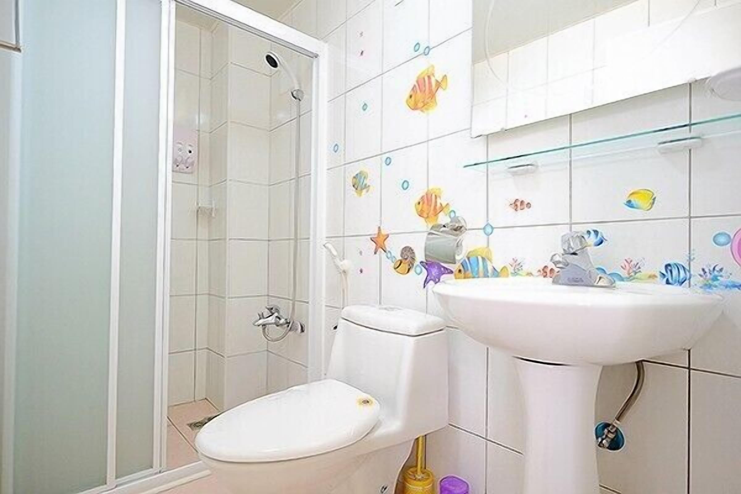 Une salle de bain avec des toilettes, un lavabo et une douche.
