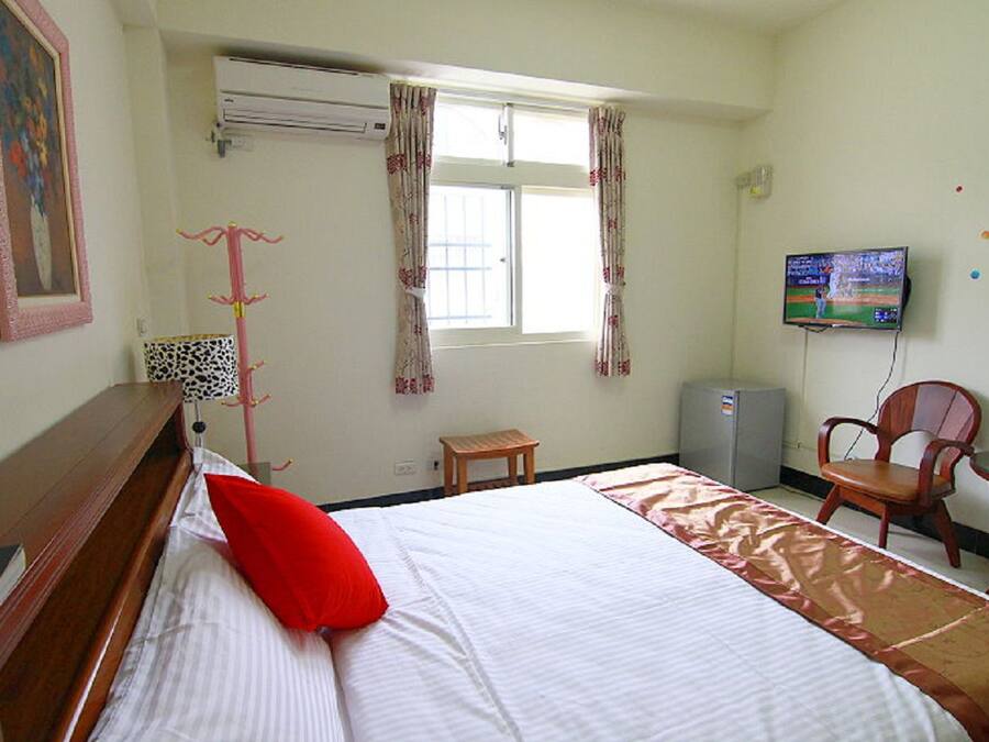Una habitación de hotel con una cama, televisión, escritorio y una silla.