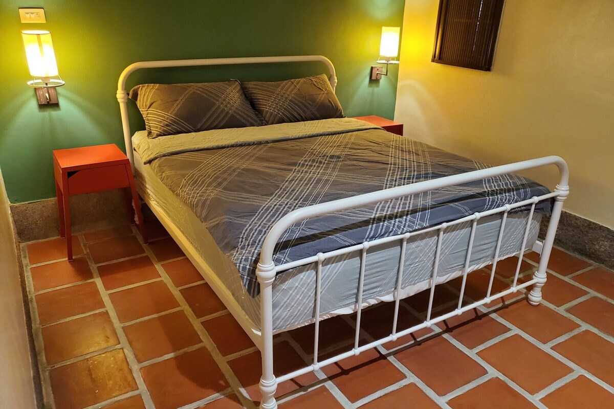 A bed with a metal frame, two nightstands, and a wall-mounted lamp.