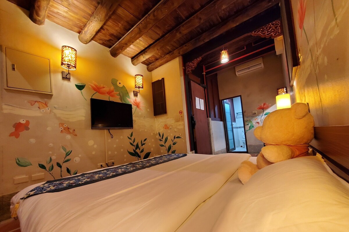 A hotel room with a bed, a television mounted on the wall, and decorative wall art.