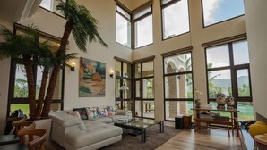 A spacious living room with a large window, a white sofa, a glass coffee table, and a wooden floor. - Villa of Permaculture (Shoufeng)